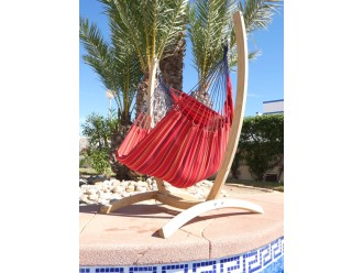 Hamac chaise rouge et support en bois devant une piscine